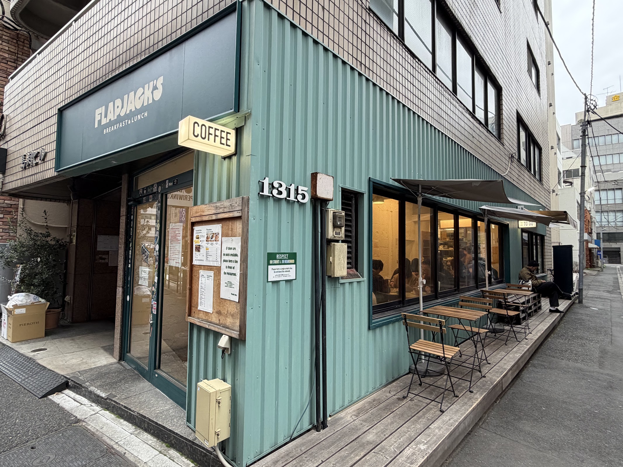 ミントグリーンの波板外壁に「1315」の番地表示、テラス席の折り畳み椅子、角地から撮影したFlapjack's全景